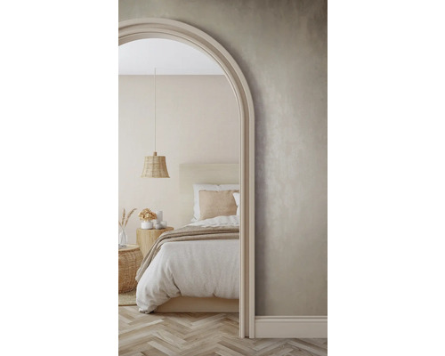 Helle Schlafzimmerszene mit Bett, Nachttisch und geflochtener Pendelleuchte, gesehen durch einen Torbogen