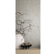 Dekorative Äste in Vase vor einer strukturierten Wand