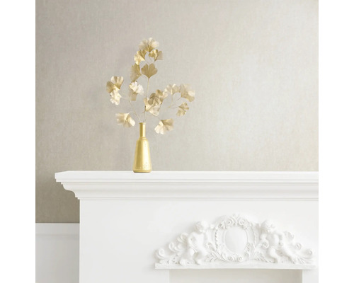 Dekoratives Stillleben mit goldener Vase und Ginkgozweigen auf einem weißen Kaminsims.