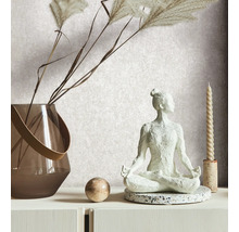 Dekorative Szene mit einer Yogafigur, einer Vase mit Ziergras, einer Kugel und einer Kerze auf einer weißen Kommode.