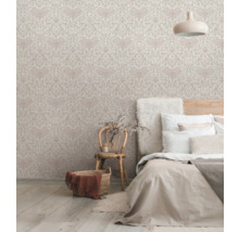 Chambre avec papier peint à motifs, lit et fauteuil en osier