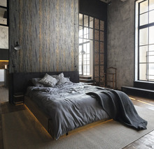 Chambre de style loft avec lit, papier peint textile et grandes fenêtres