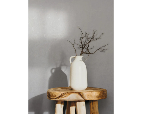 Dekorative Zweige in einer weißen Vase auf einem Holzhocker