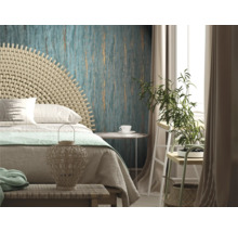 Chambre claire avec lit, tête de lit en rotin, papier peint à motifs et plante d''intérieur