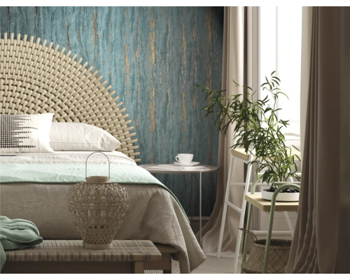 Chambre claire avec lit, tête de lit en rotin, papier peint à motifs et plante d''intérieur