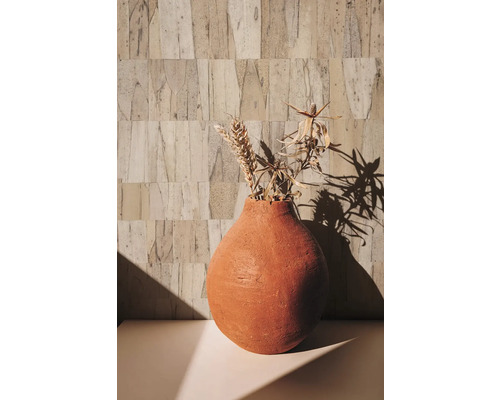 Vase décoratif avec fleurs séchées sur une table devant un mur structuré