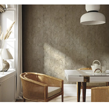 Salon avec carrelage mural aspect pierre, fauteuils en rotin et table à manger avec service à thé.