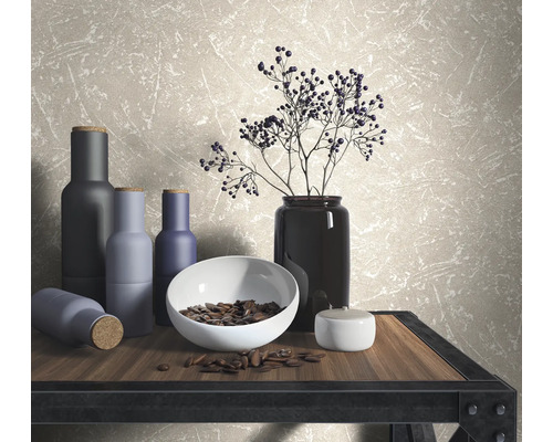 Dekorative Szene mit Vasen, Schale und Zweigen auf einem Tisch vor einer Wandtapete.