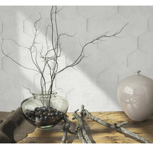 Scène décorative avec vase en verre, branches et vase en céramique sur une table en bois devant un mur avec des carreaux hexagonaux.