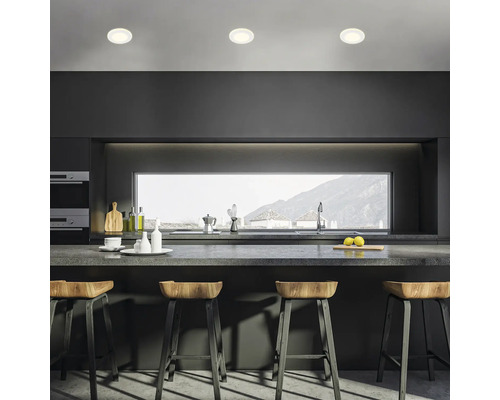 Helle Küche mit drei Deckenleuchten, Barhockern und grossem Fenster