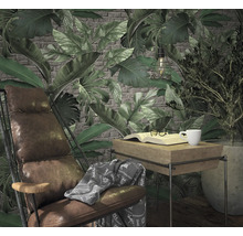 Scène de salon avec fauteuil, table, livre, tasse et plantes devant un papier peint à motifs de feuilles