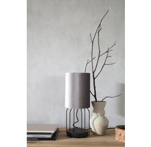 Dekorative Tischleuchte mit Lampenschirm aus Stoff und Metallgestell auf einem Tisch