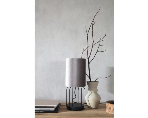 Dekorative Tischleuchte mit Lampenschirm aus Stoff und Metallgestell auf einem Tisch