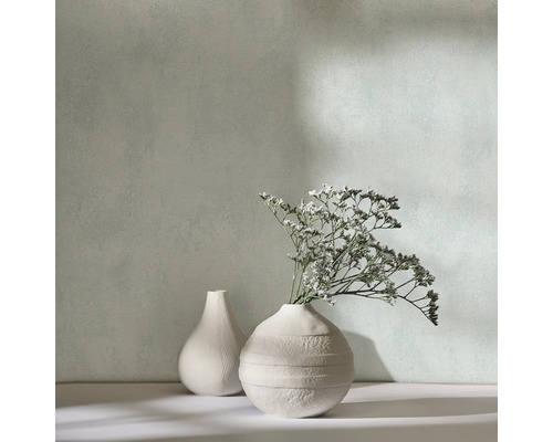 Zwei dekorative Vasen mit Trockenblumen vor einer Wand