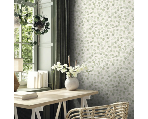 Szene mit einem Schreibtisch, einem Fenster und einer Wand mit Eukalyptus-Tapete.