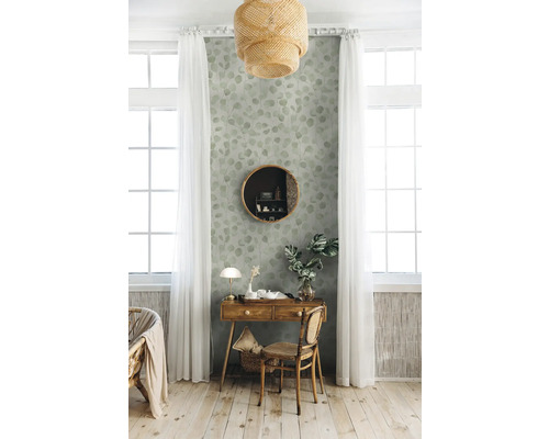 Dekoratives Interieur mit einem Holztisch, einem runden Spiegel und einer Tapete mit Blättermuster in einem hellen Raum