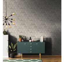 Raumansicht mit gemusterter Tapete, Kommode und Dekorationsartikeln.