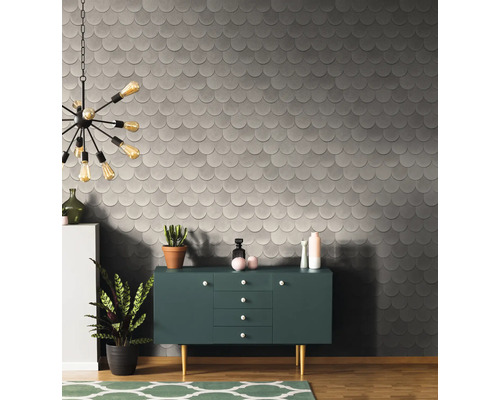 Raumansicht mit gemusterter Tapete, Kommode und Dekorationsartikeln.