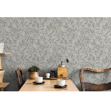 Graue Blättertapete hinter einem Holztisch in einem hellen Raum.