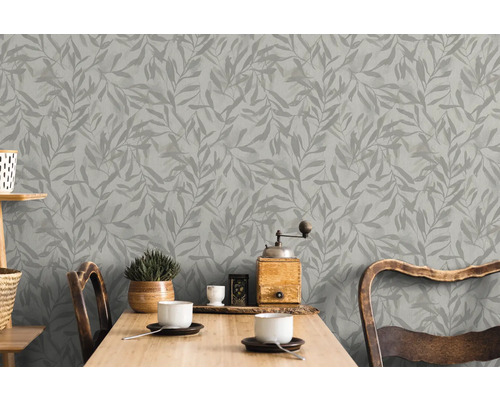 Graue Blättertapete hinter einem Holztisch in einem hellen Raum.
