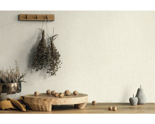 Dekorative Szene mit Pflanzen, Nüssen und Holzobjekten auf einem Tisch vor einer Wand