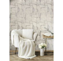 Helles Wohnzimmer mit Sessel, Decke, Kissen, Beistelltisch, Blumen und gemusterter Tapete