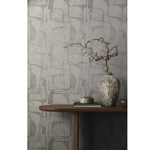 Eine Wand mit grafischer Tapete, dekoriert mit einer Holzvase auf einem Tisch.