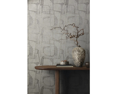 Eine Wand mit grafischer Tapete, dekoriert mit einer Holzvase auf einem Tisch.