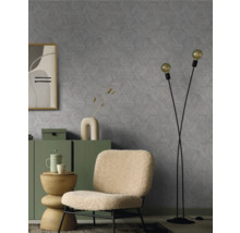 Salon avec un fauteuil, un lampadaire et une commode devant un mur avec un motif géométrique.