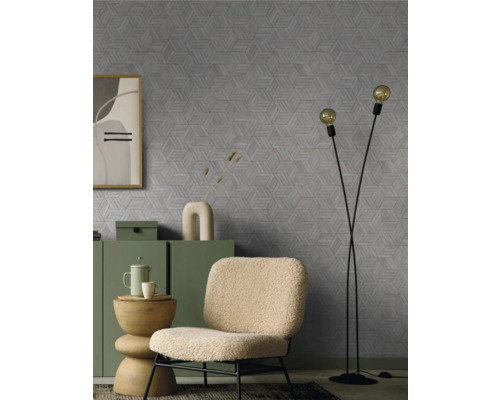 Salon avec un fauteuil, un lampadaire et une commode devant un mur avec un motif géométrique.