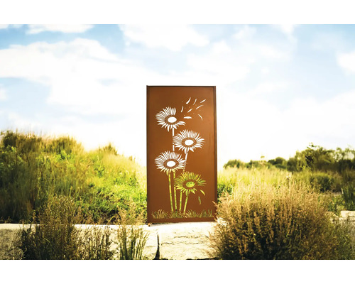 Écran de jardin décoratif en métal avec motif floral devant un paysage naturel