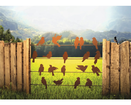 Dekorative Vogelsilhouetten auf einem Zaun vor einer grünen Landschaft.