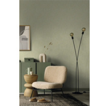 Salon avec papier peint à motifs verts, fauteuil, lampadaire et tapis