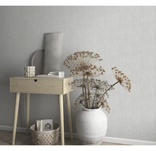 Scène décorative avec une petite table en bois, un vase avec des fleurs séchées et du papier peint à motifs
