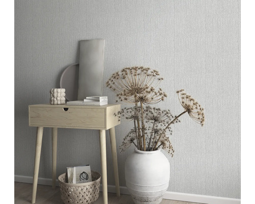 Scène décorative avec une petite table en bois, un vase avec des fleurs séchées et du papier peint à motifs