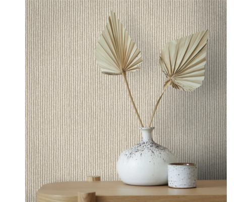 Gros plan d''un mur avec du papier peint à motif tricoté, décoré d''un vase et de feuilles de palmier séchées sur une table en bois.