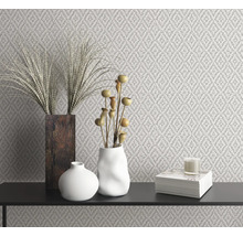 Intérieur décoratif avec papier peint à motifs, vases, décoration et bougie sur une surface noire.