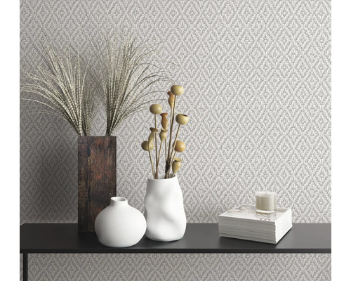 Intérieur décoratif avec papier peint à motifs, vases, décoration et bougie sur une surface noire.