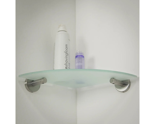 Eckregal aus Glas mit Pflegeprodukten an einer weißen Wand