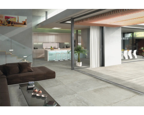 Espace de vie lumineux avec carrelage au sol imitation béton, canapé et cuisine ouverte