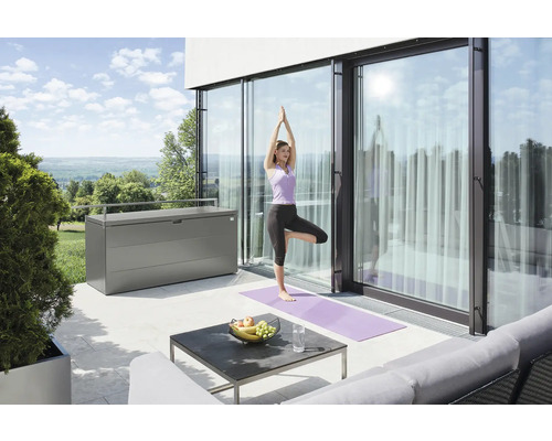Scène avec une femme faisant du yoga sur une terrasse à côté d''un coffre de rangement