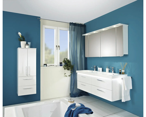 Modernes Badezimmer mit weissem Waschtisch, Spiegelschrank, Hochschrank und Badewanne vor blauer Wand