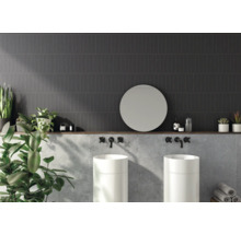 Salle de bains avec carreaux muraux foncés, deux lavabos, miroir rond et décoration