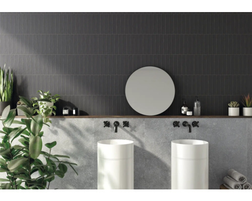 Badezimmer mit dunklen Wandfliesen, zwei Waschbecken, rundem Spiegel und Dekoration