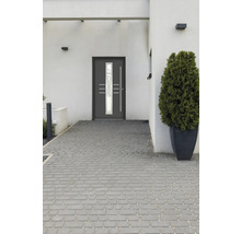Graue Haustür mit Glaseinsatz in einer modernen Hausfassade mit Pflastersteinen