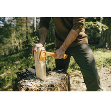 Mann spaltet Holz mit einer Fiskars Spaltaxt auf einem Baumstumpf