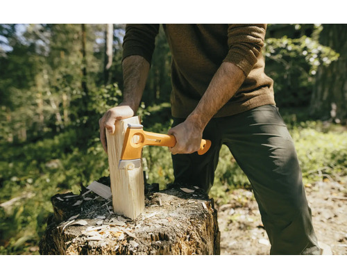 Mann spaltet Holz mit einer Fiskars Spaltaxt auf einem Baumstumpf