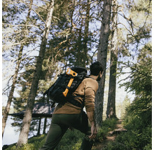 Mann mit Rucksack und Axt wandert durch den Wald