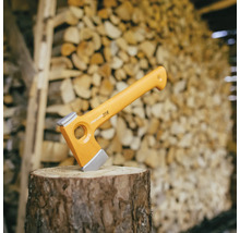 Fiskars Spaltaxt auf einem Holzscheit vor einem Holzstapel