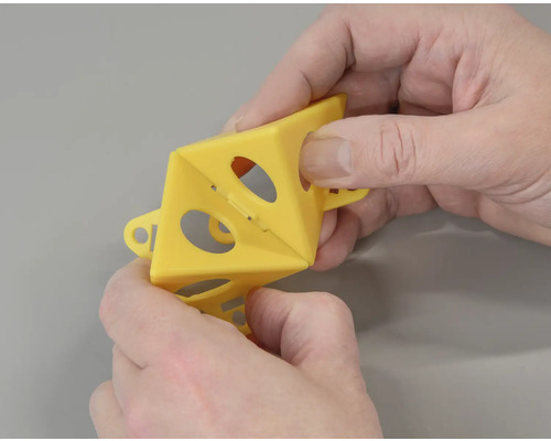 Hände falten einen gelben Insektenschutz mit Löchern